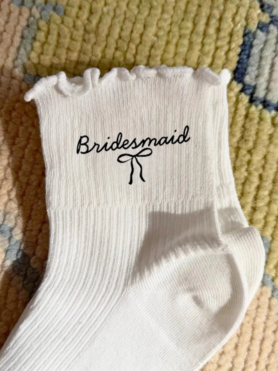 White wedding day socks with 'Bride Team' and 'Maid of Honor' lettering, shown on bridal party gift display.