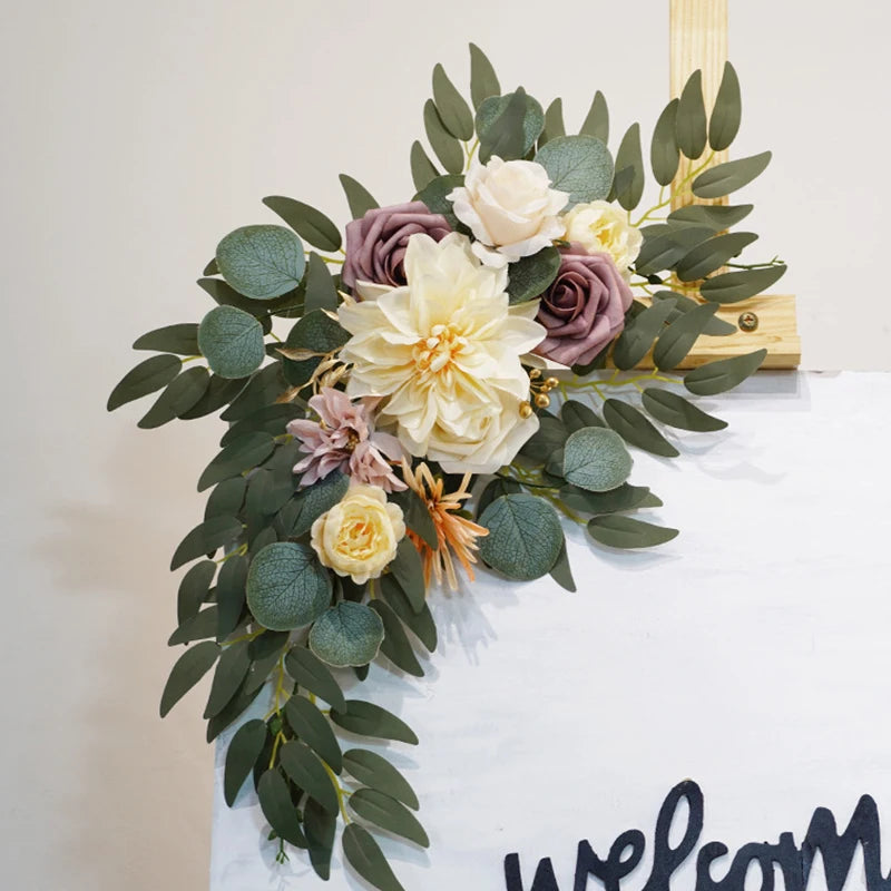 Artificial silk floral swag pair in champagne rose, shown on rustic wedding welcome sign backdrop.