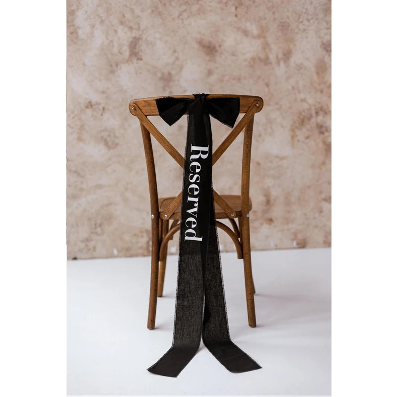 Elegant black 'Reserved' wedding chair seating ribbon, shown on ceremony chair display.