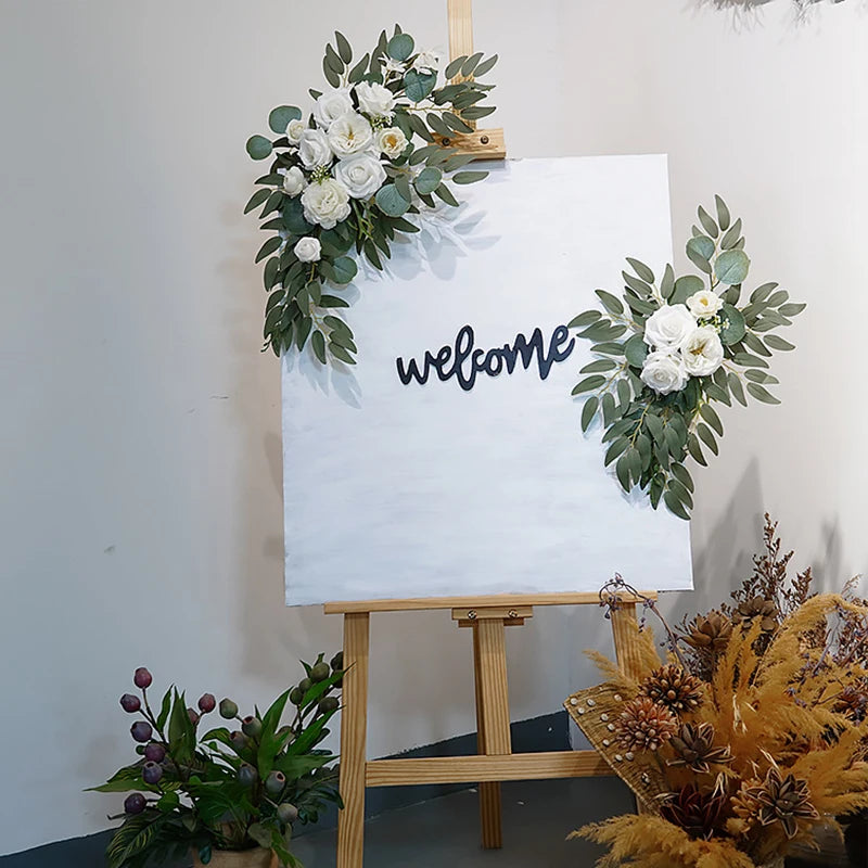 Artificial silk floral swag pair in champagne rose, shown on rustic wedding welcome sign backdrop.