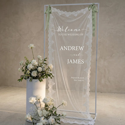 Personalized lace fabric wedding welcome banner with embroidered custom names and date, shown on outdoor ceremony display.