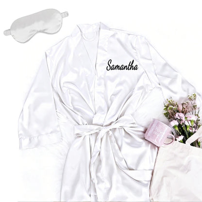 Personalized soft satin bridesmaid robe in custom pink with matching eye mask, shown on bachelorette gift display.