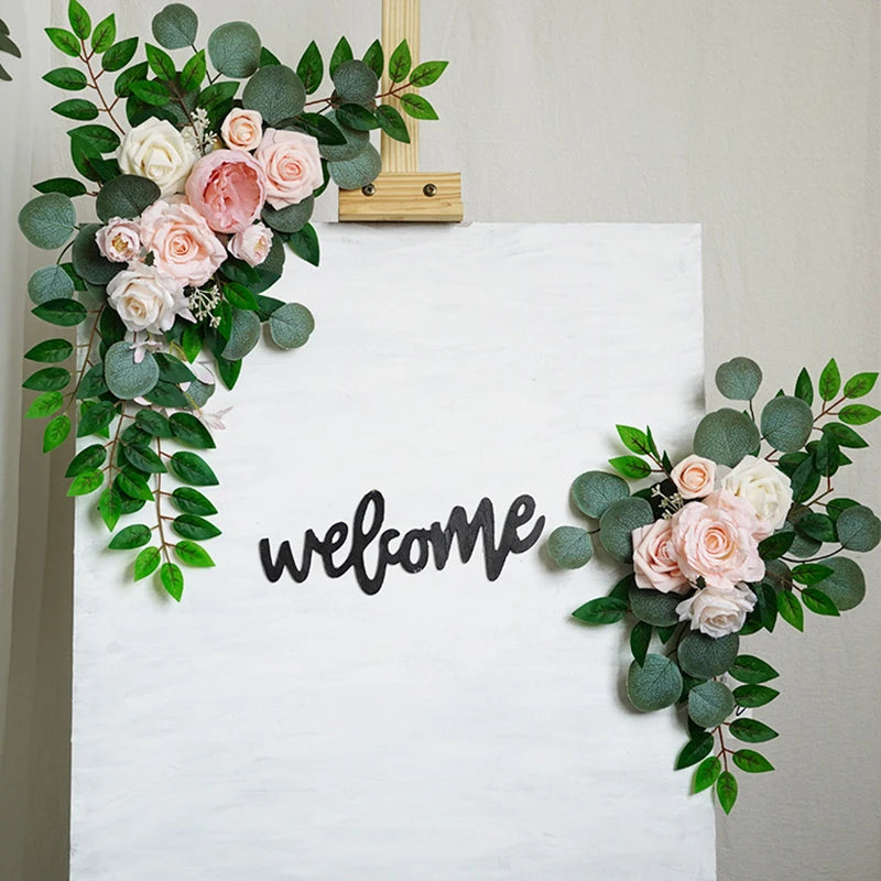 Artificial silk floral swag pair in champagne rose, shown on rustic wedding welcome sign backdrop.
