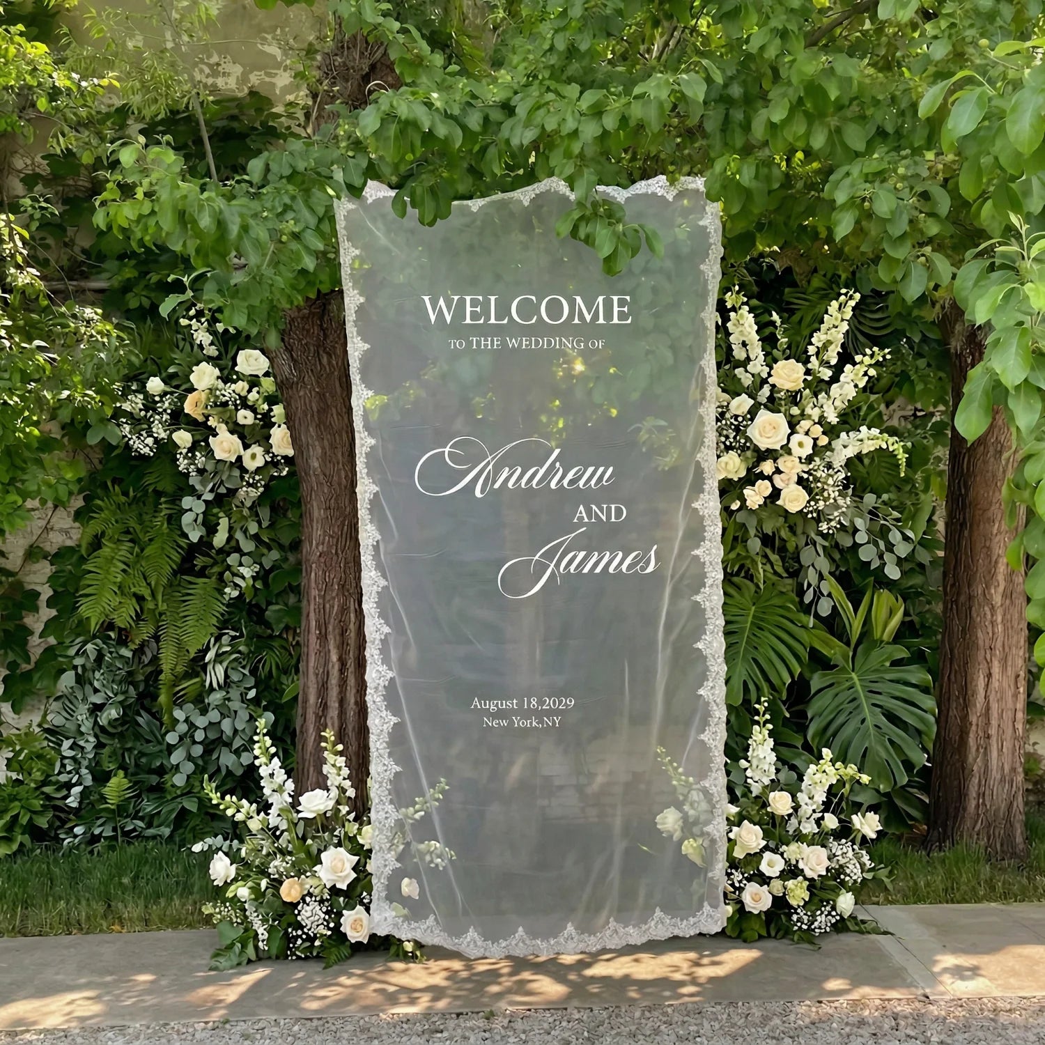 Personalized lace fabric wedding welcome banner with embroidered custom names and date, shown on outdoor ceremony display.