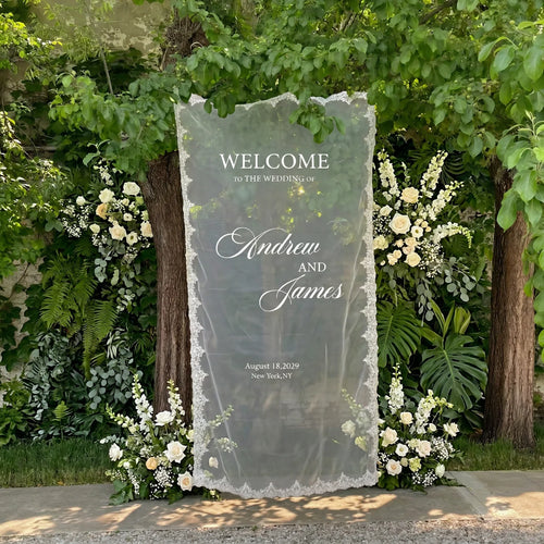 Personalized lace fabric wedding welcome banner with embroidered custom names and date, shown on outdoor ceremony display.
