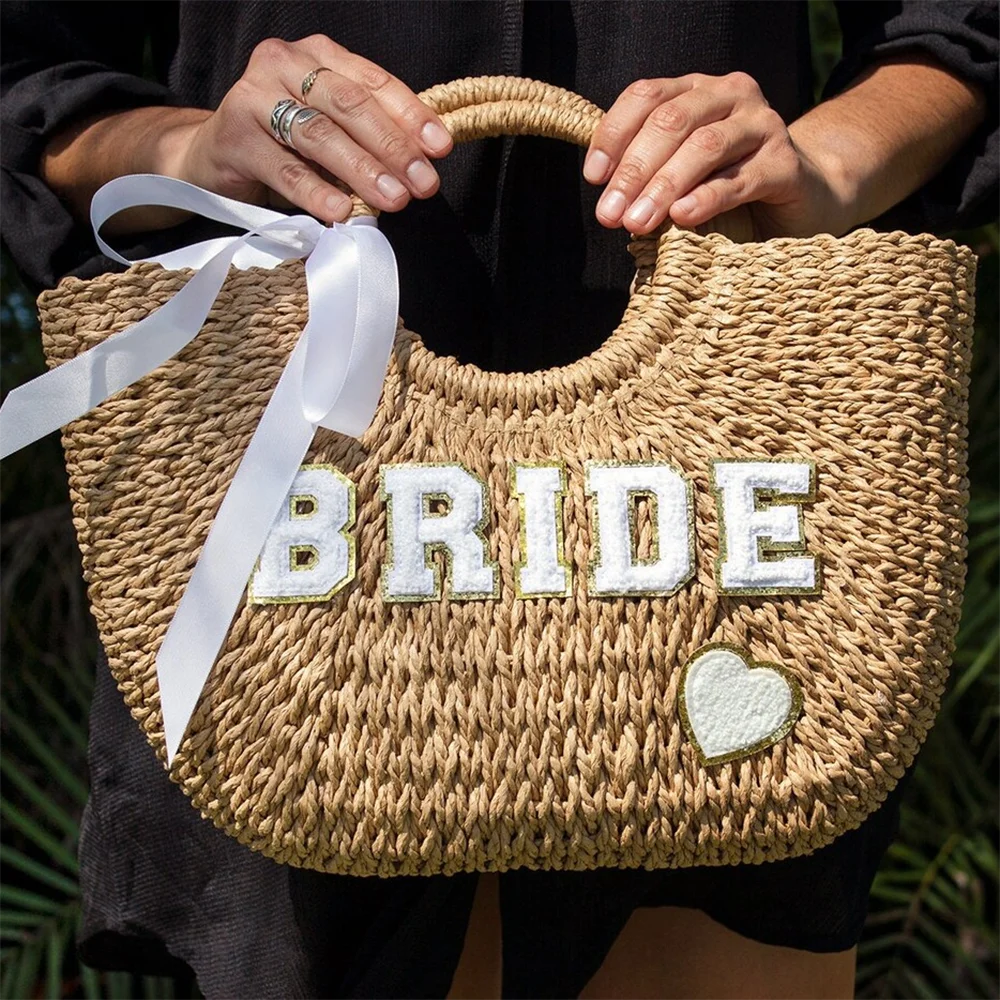 Bride straw tote beach bag with 'Bride' lettering, shown on bachelorette honeymoon accessory display.