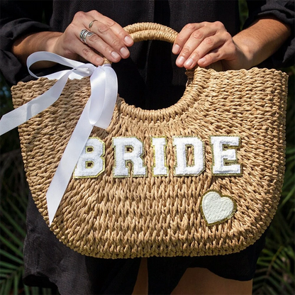 Bride straw tote beach bag with 'Bride' lettering, shown on bachelorette honeymoon accessory display.