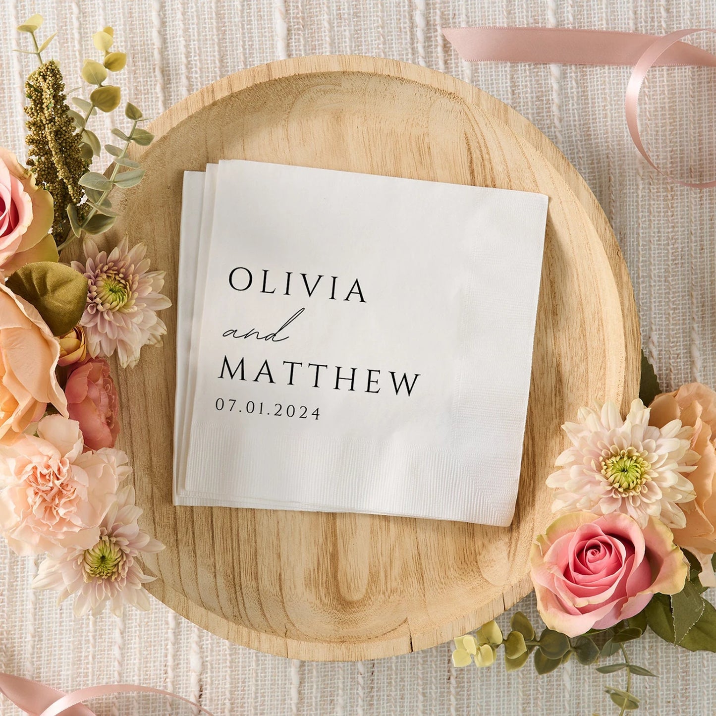 Custom monogram cocktail napkins personalized with names and wedding date, shown on wedding reception bar display.