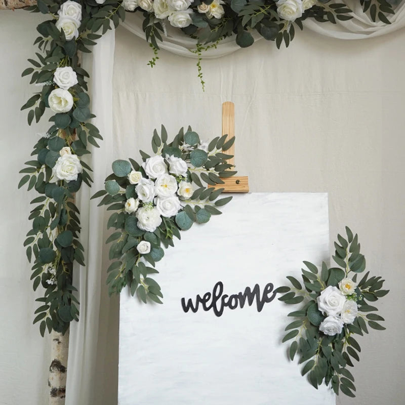 Artificial silk floral swag pair in champagne rose, shown on rustic wedding welcome sign backdrop.