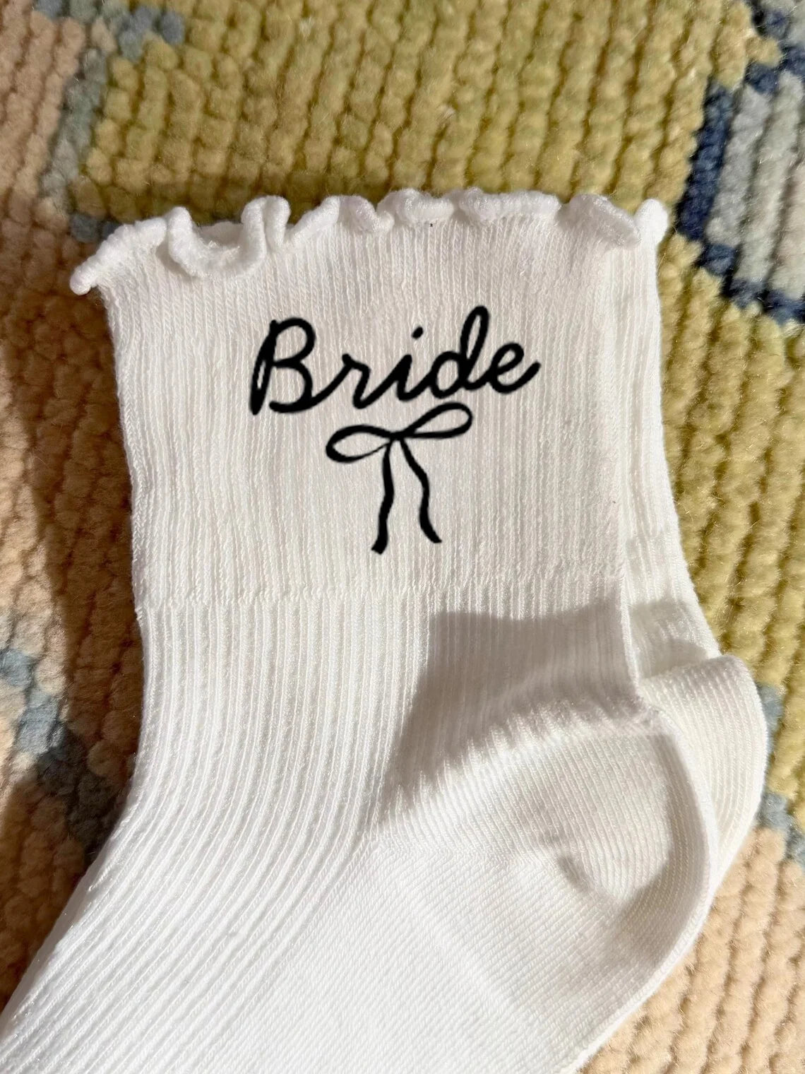 White wedding day socks with 'Bride Team' and 'Maid of Honor' lettering, shown on bridal party gift display.