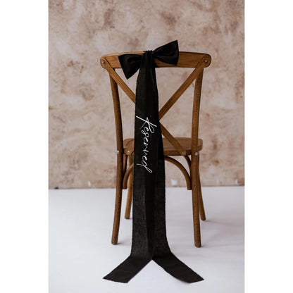 Elegant black 'Reserved' wedding chair seating ribbon, shown on ceremony chair display.