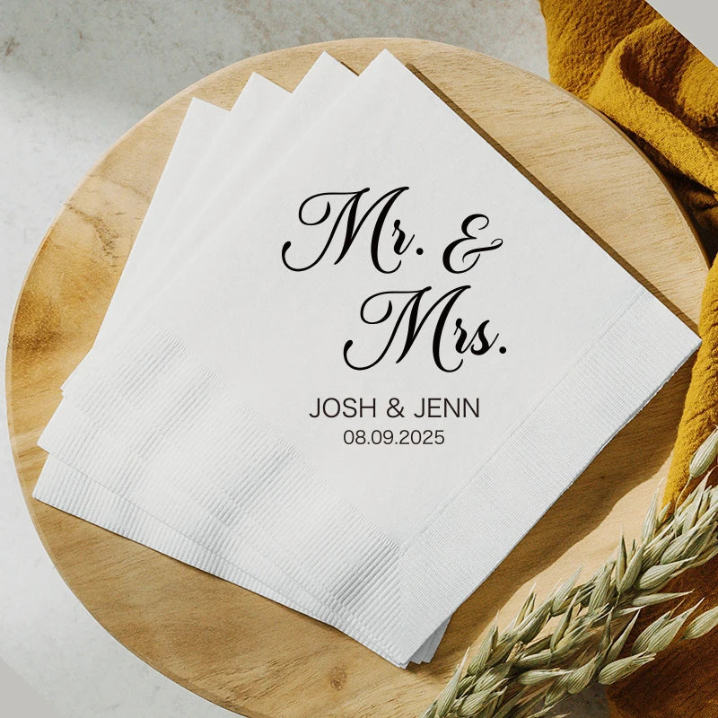 Custom monogram cocktail napkins personalized with names and wedding date, shown on wedding reception bar display.