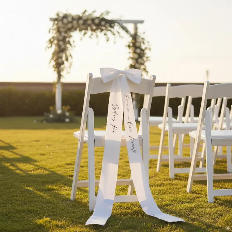 Personalized white memorial chair ribbon with 'Forever In Our Hearts' printed lettering, shown on reserved wedding ceremony chair.