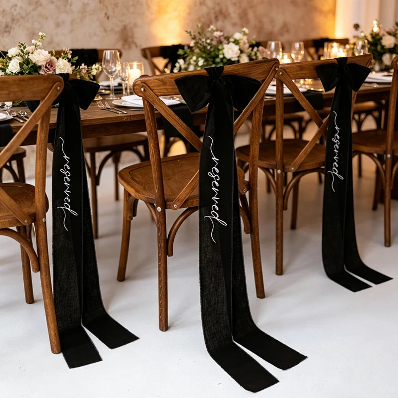 Elegant black 'Reserved' wedding chair seating ribbon, shown on ceremony chair display.