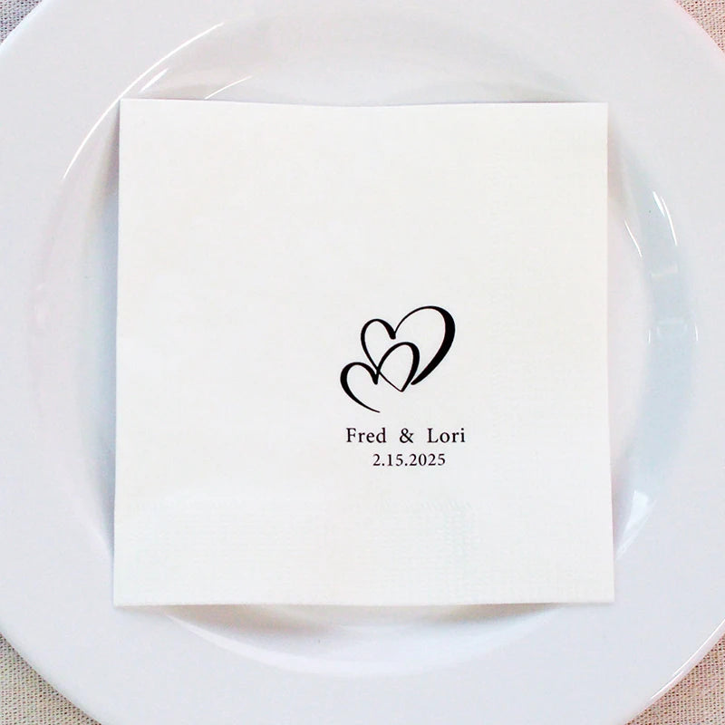 Custom monogram cocktail napkins personalized with names and wedding date, shown on wedding reception bar display.