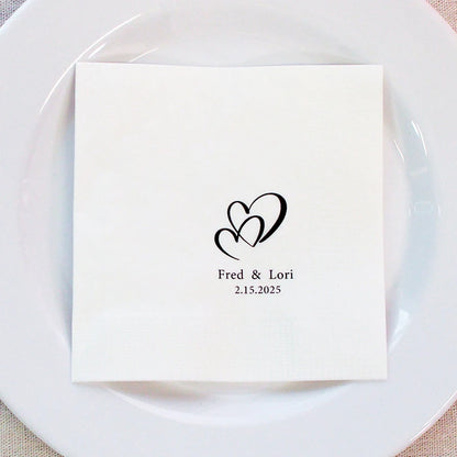 Custom monogram cocktail napkins personalized with names and wedding date, shown on wedding reception bar display.