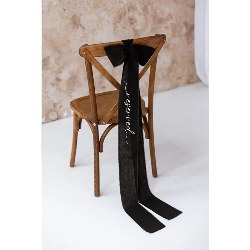 Elegant black 'Reserved' wedding chair seating ribbon, shown on ceremony chair display.