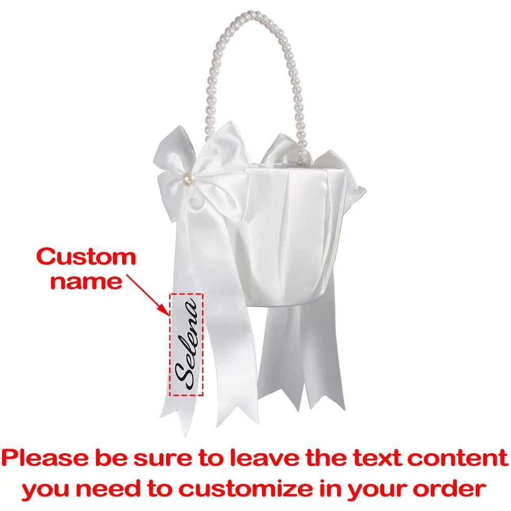Personalized white flower girl basket and ring bearer pillow set with custom lettering, shown on wedding ceremony display.