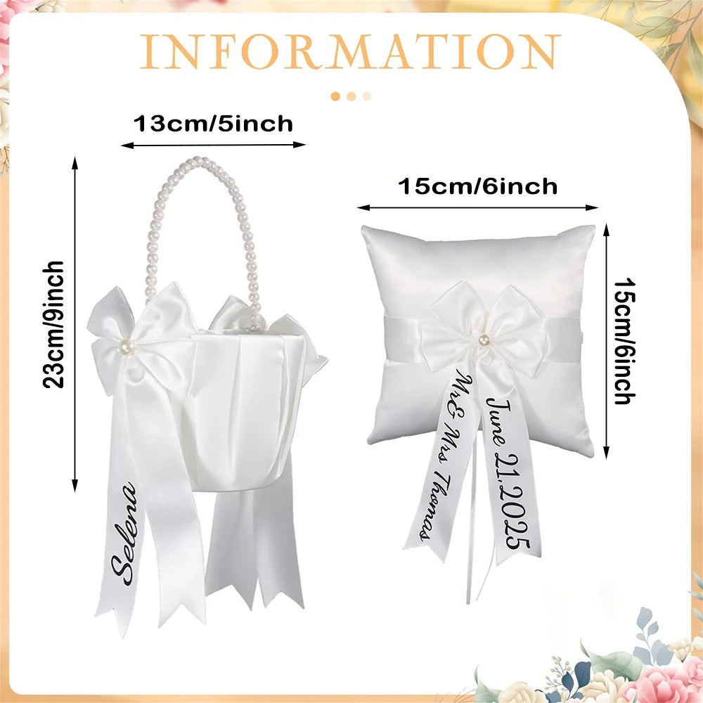 Personalized white flower girl basket and ring bearer pillow set with custom lettering, shown on wedding ceremony display.