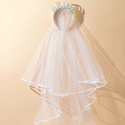 Bride to be pearl curvy veil in white tulle with satin bow, shown on bachelorette headpiece display.
