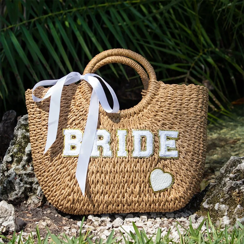 Bride straw tote beach bag with 'Bride' lettering, shown on bachelorette honeymoon accessory display.