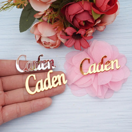 Custom acrylic mirror name tags in black, gold, silver and rose gold with personalized lettering, shown on wedding place card display.