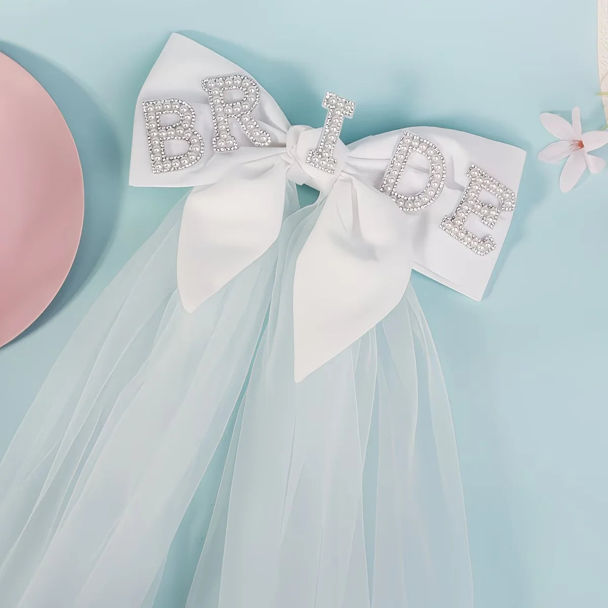 Bride to be pearl curvy veil in white tulle with satin bow, shown on bachelorette headpiece display.