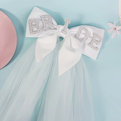 Bride to be pearl curvy veil in white tulle with satin bow, shown on bachelorette headpiece display.