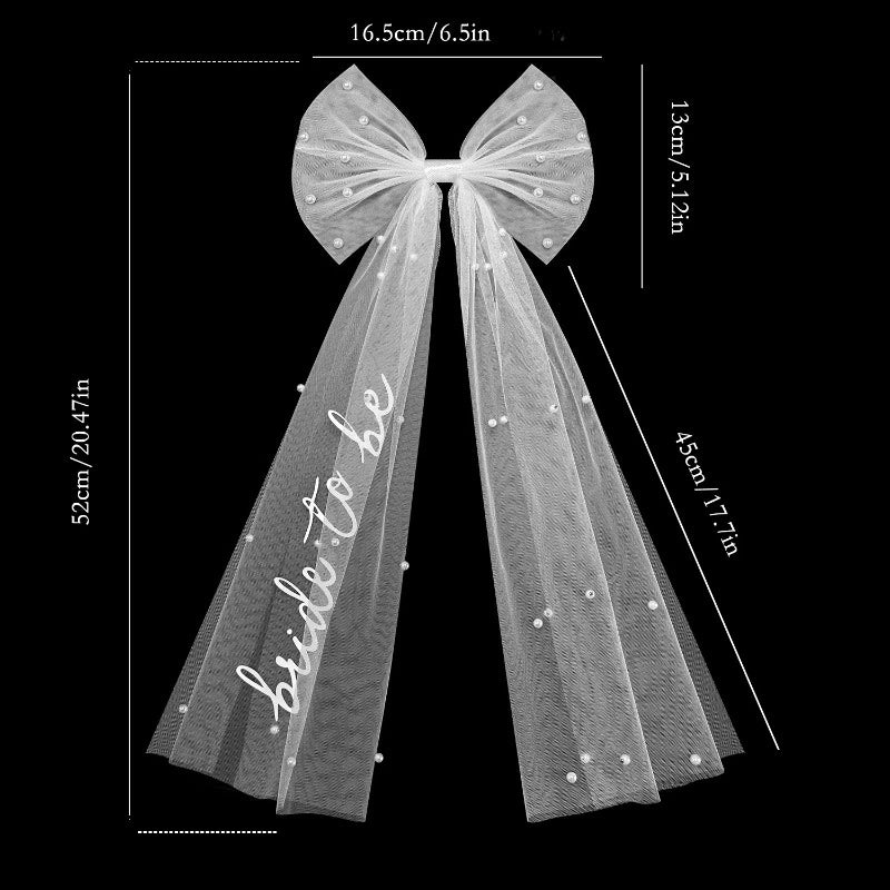 White pearl hair bow clip with attached tulle veil, shown on bride-to-be bachelorette accessory display.
