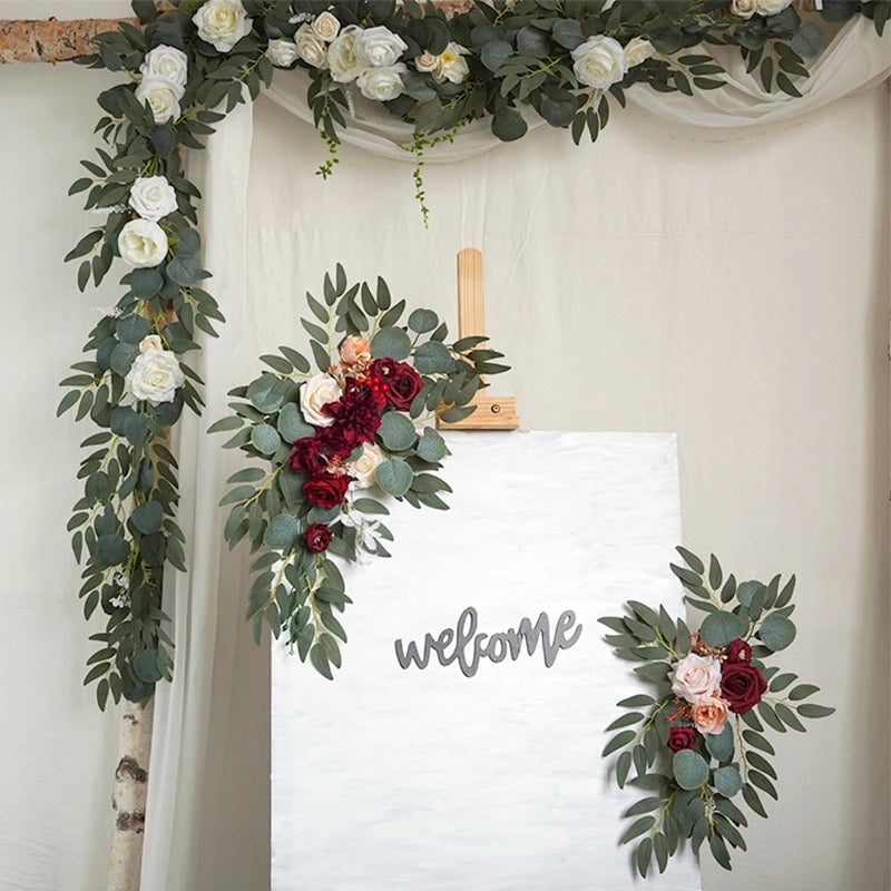 Artificial silk floral swag pair in champagne rose, shown on rustic wedding welcome sign backdrop.