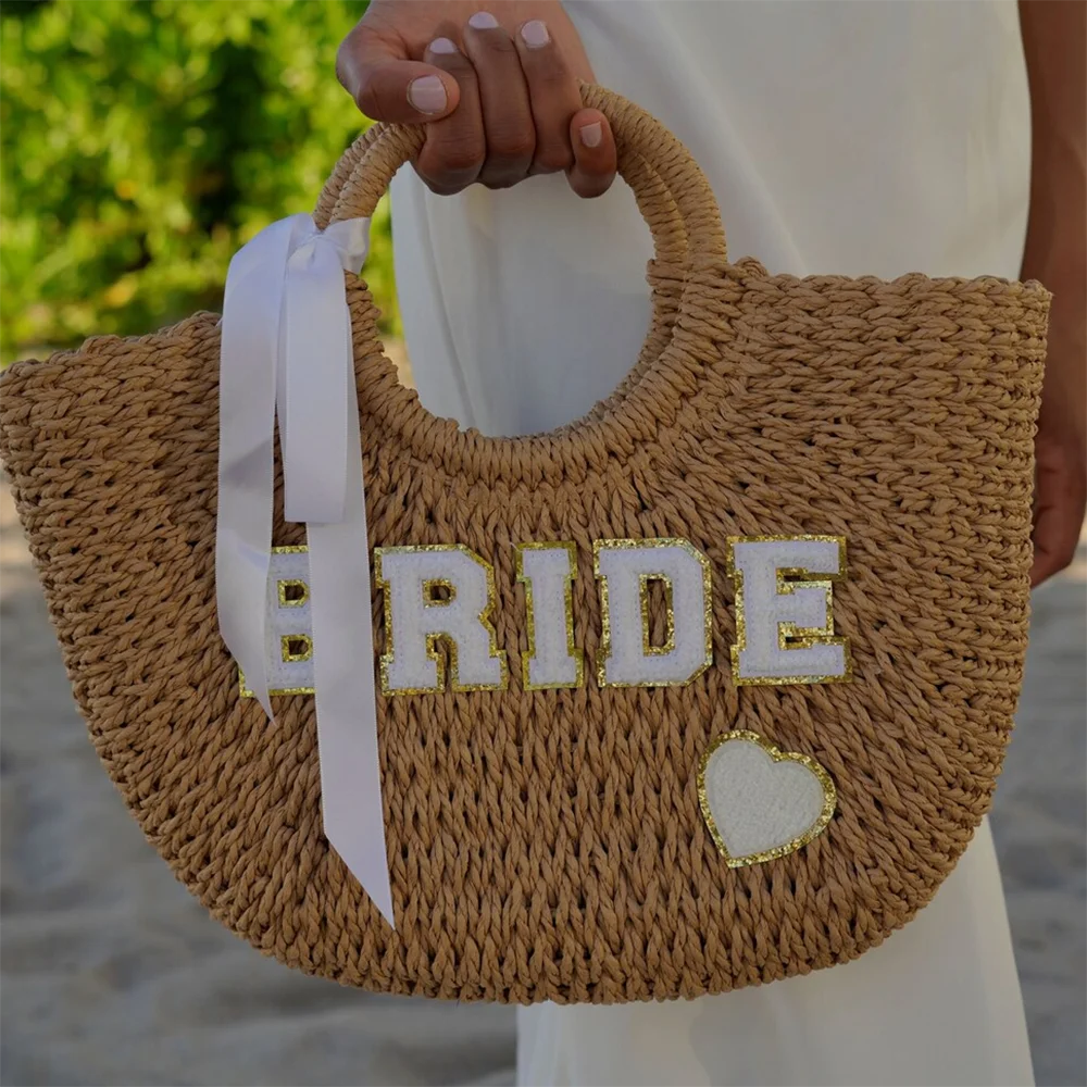 Bride straw tote beach bag with 'Bride' lettering, shown on bachelorette honeymoon accessory display.
