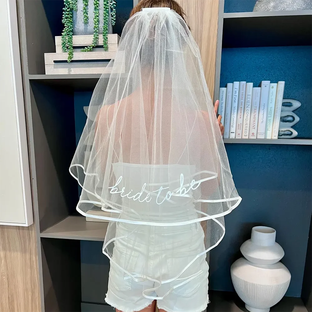 Bride to be pearl curvy veil in white tulle with satin bow, shown on bachelorette headpiece display.